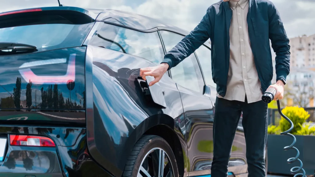 man closing cars charge socket holding charger charge station